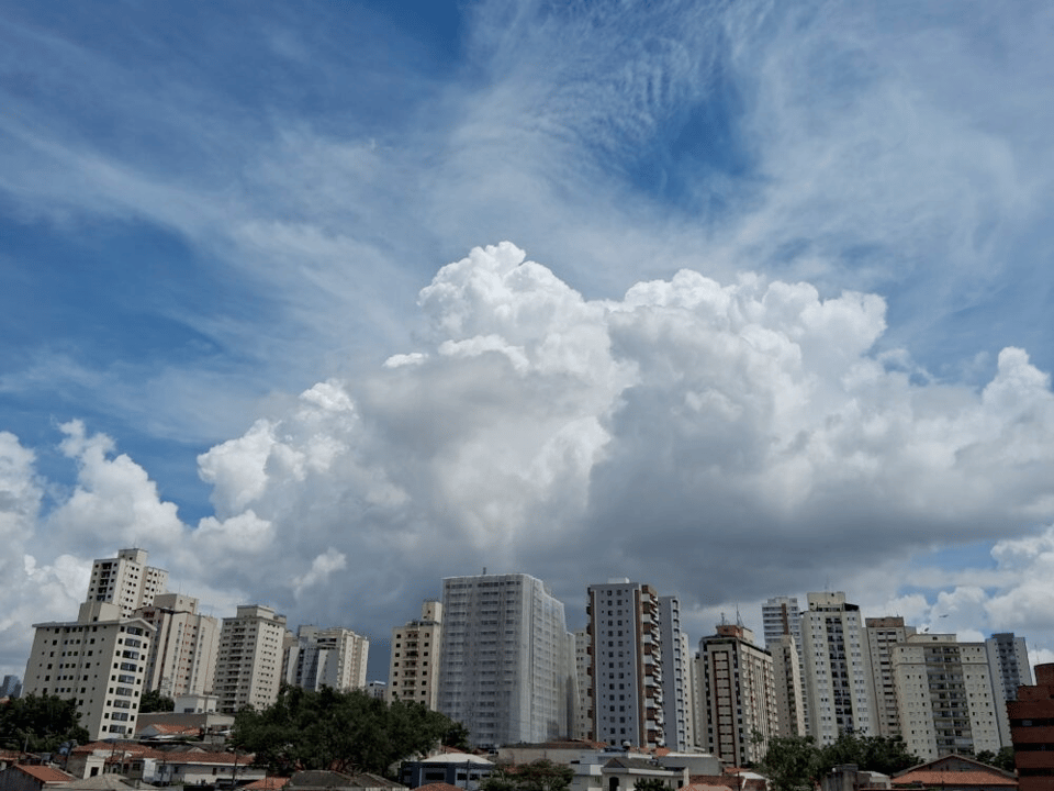 A photo of several white apartment buildings, with massive puffy clouds looming over them