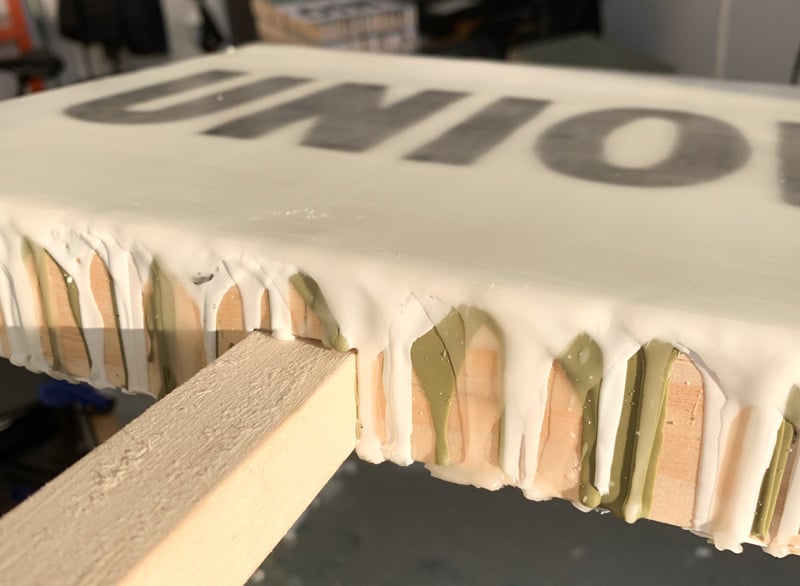 A sideview of a painting showing how messy the edges are. There's wax oozing everywhere. It might look edible, though?