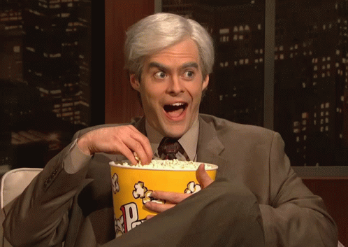 Gif mostra um homem de cabelos brancos sorrindo e comendo pipoca, muito entretido