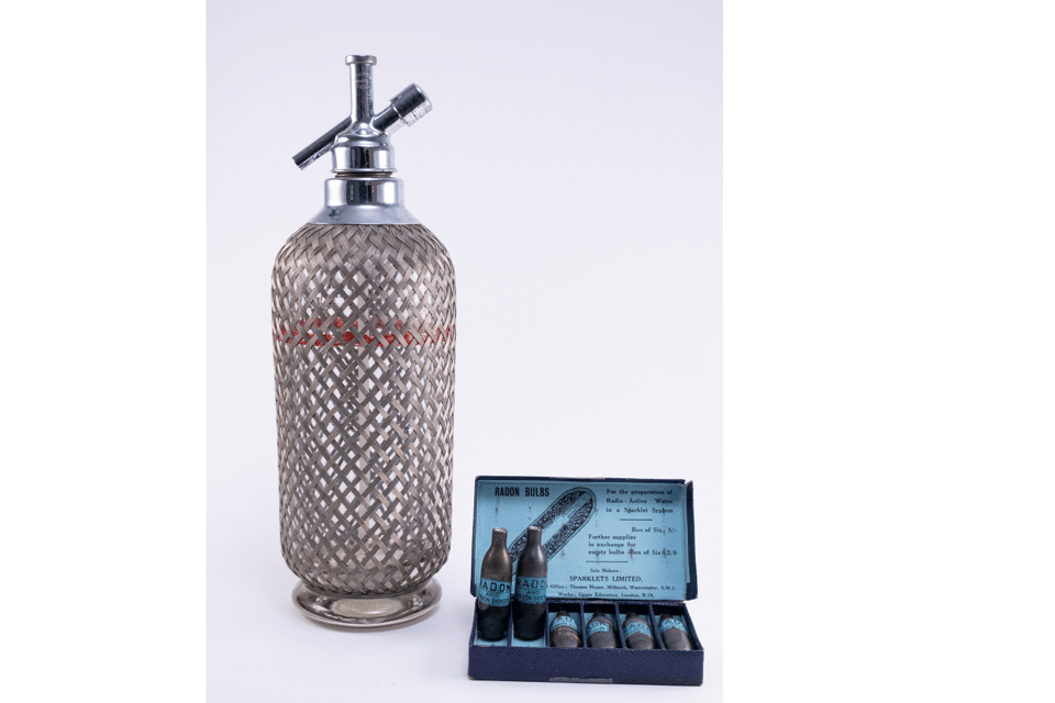 Colour photograph of the Sparklets system. Image shows a soda spray bottle and a box containing 6 soda syphons.