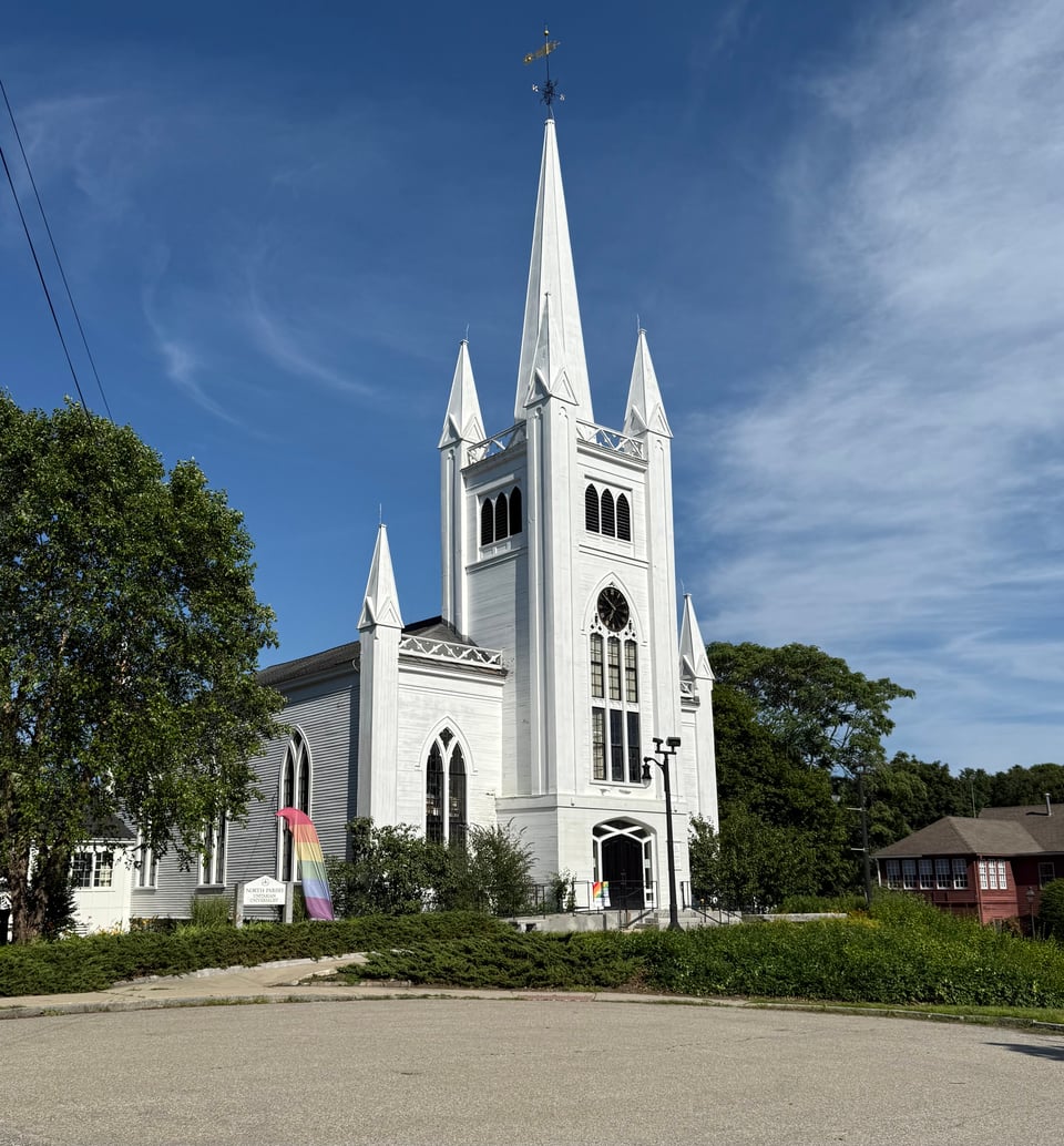 photo of a white church with a high steeple, against a blue sky