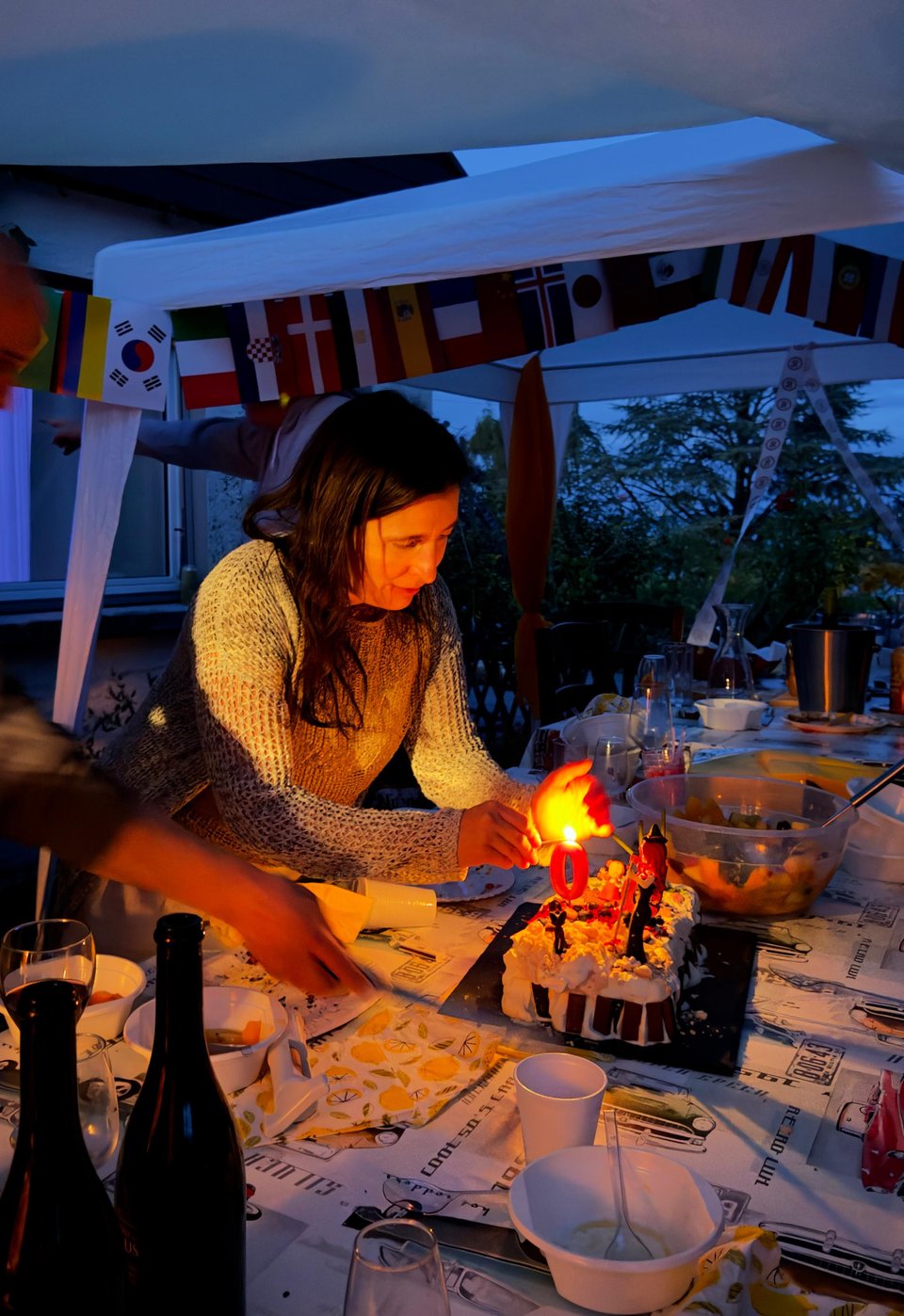 A woman lights the birthday candle on her cake.