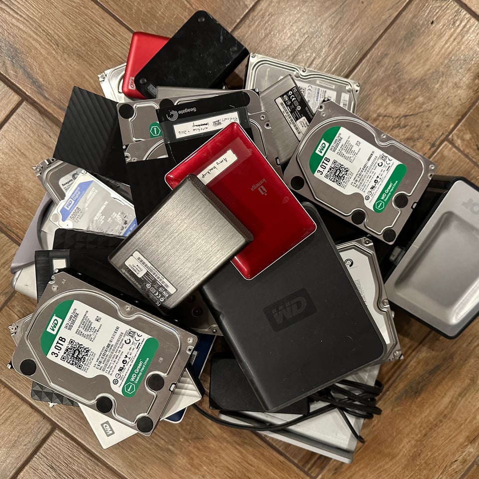 Photo of a pile of old hard drives, some internal, some with external cases.