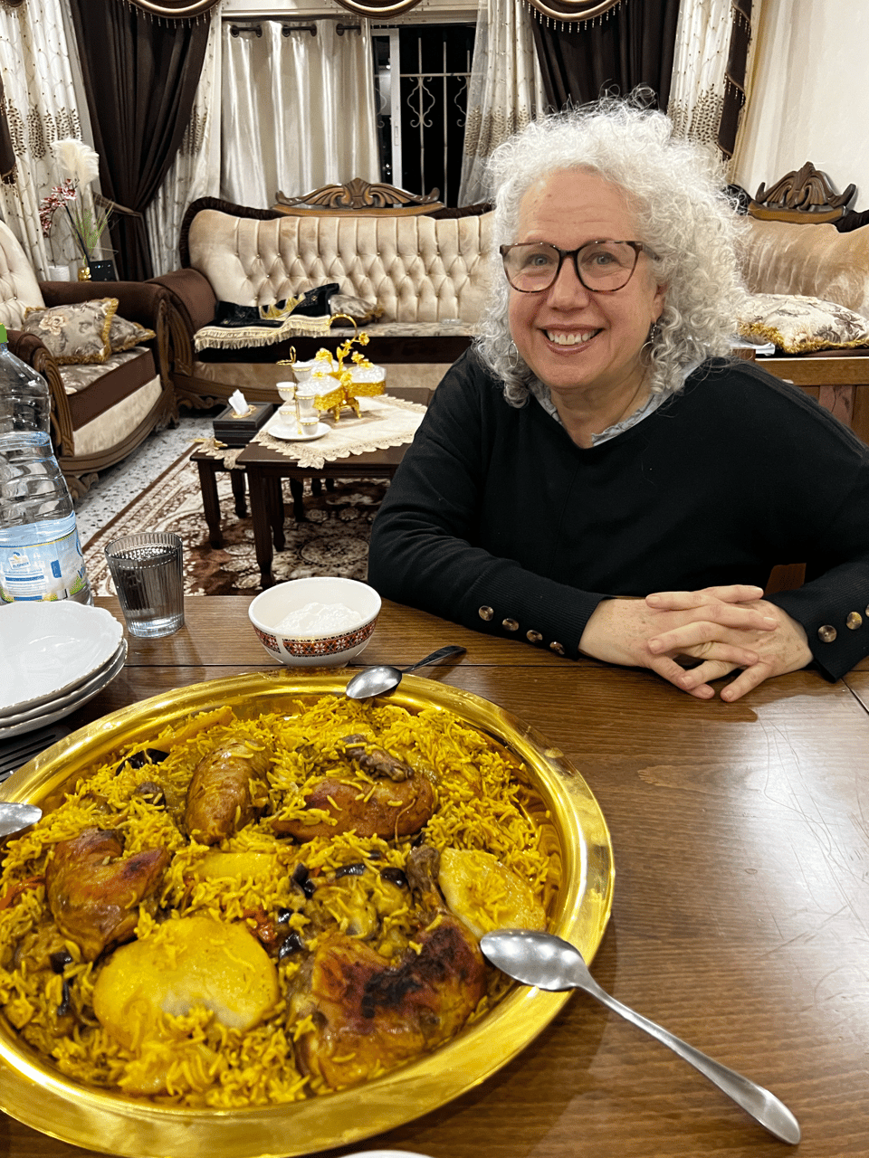 Me sitting at a table with a large serving dish of rice, chicken, and vegetables