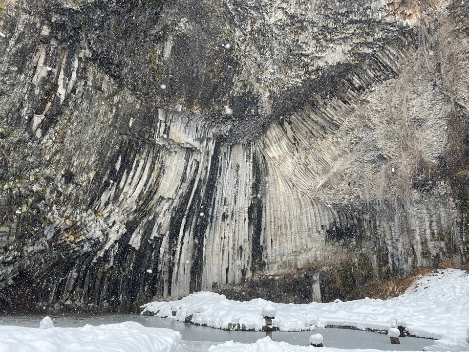 Seiryudo Cave. A frozen pool of water sits at the bottom of a massive wall of long, hexagonal basalt.
