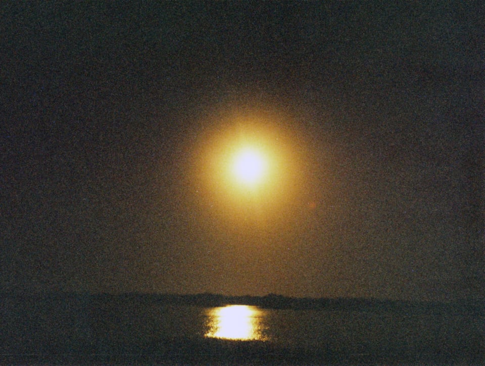 the moon rising over a body of water