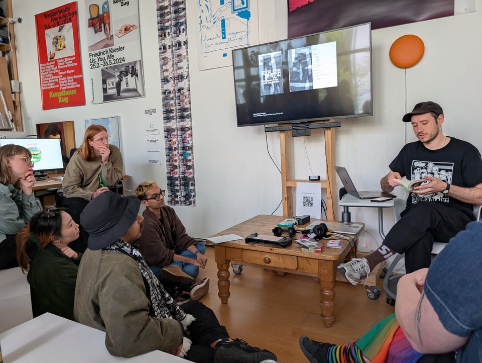 A speaker flips through a book as a he speaks to an audience.