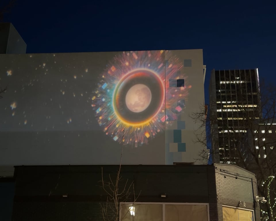 Projection on side of building. Projected image is the moon with colorful rings and shapes around it.