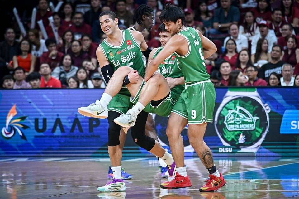 two filipino basketball players carry a teammate off the court, all of them grinning