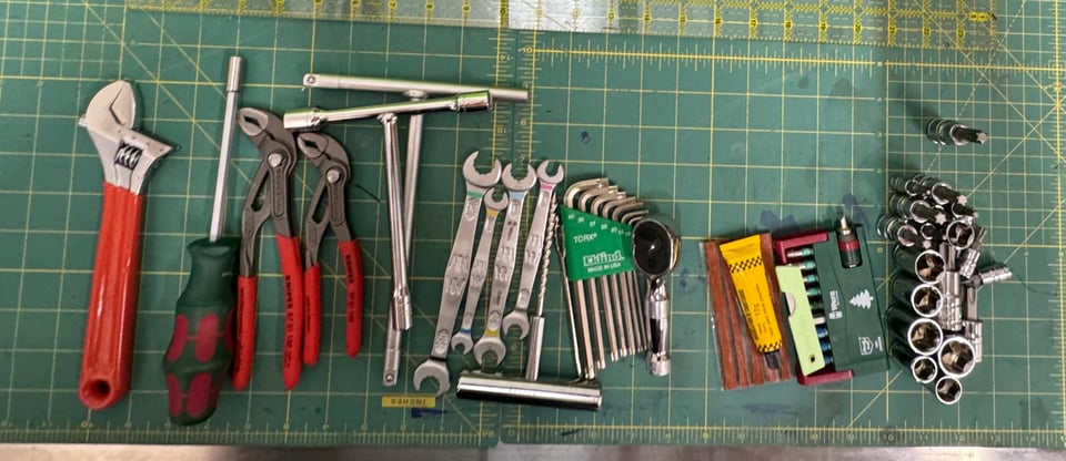 An array of hand tools, on a green cutting mat.