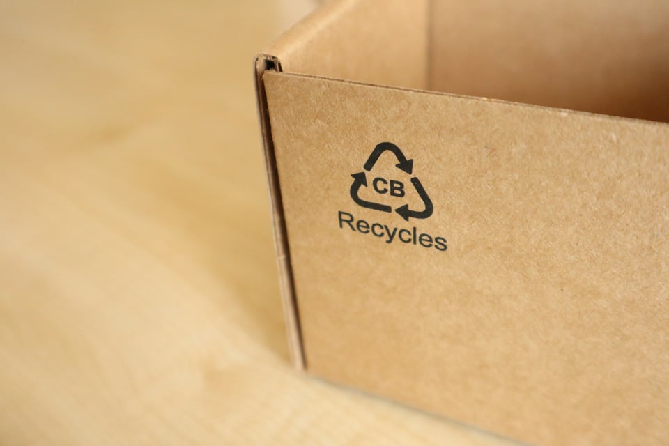 A close-up of a cardboard box with the triangular recycling logo on the side. Photo by Ochir-Erdene Oyunmedeg on Unsplash.