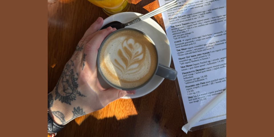 The author's tattooed hand holding a mug of coffee