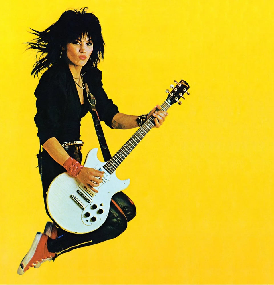 The cover of Joan Jett's third album (entitled "Album"), which is a photo of Joan leaping in the air, knees bent, in front of a solid yellow background while playing a white Gibson guitar. She's wearing her Norma Kamali black leather jumpsuit and red Pro Keds hightops. I can't definitively identify the guitar, though it seems like it might be the Joan Jett Blackheart model, similar to the Les Paul double cutaway except that the cutaways are symmetrical. She looks like what she was at the time of the photograph; i.e., one of the three coolest rock performers in the world. (The other two were Chrissie Hynde and Debbie Harry.)