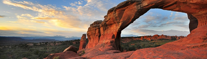 a red rock arch in the desert at sunrise