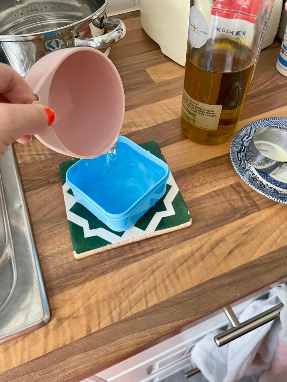 One cup of water pouring into a blue container of approximate size