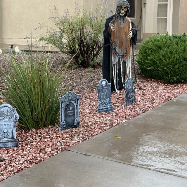halloween skeleton dressed as a ghoul. 4 tombstones sit in front of it.