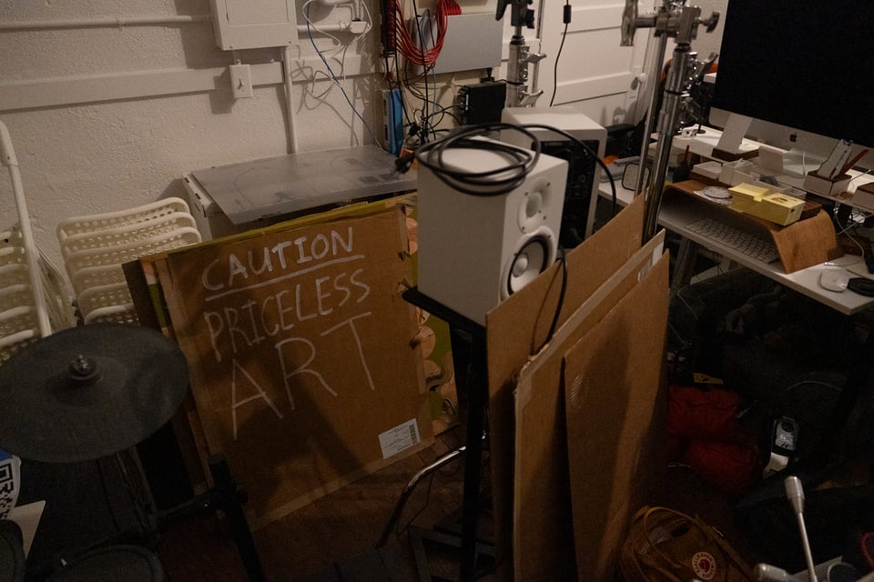 A sign that says “caution: priceless art“ in a messy room.