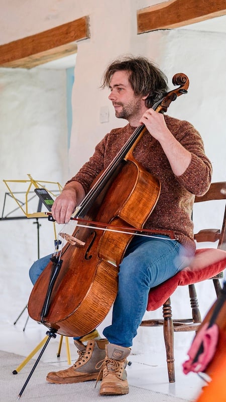 Seated cellist with instrument.