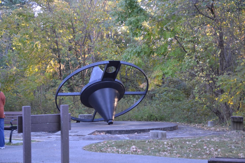 A sculpture that resembles a giant, reversible spinning top on its side.