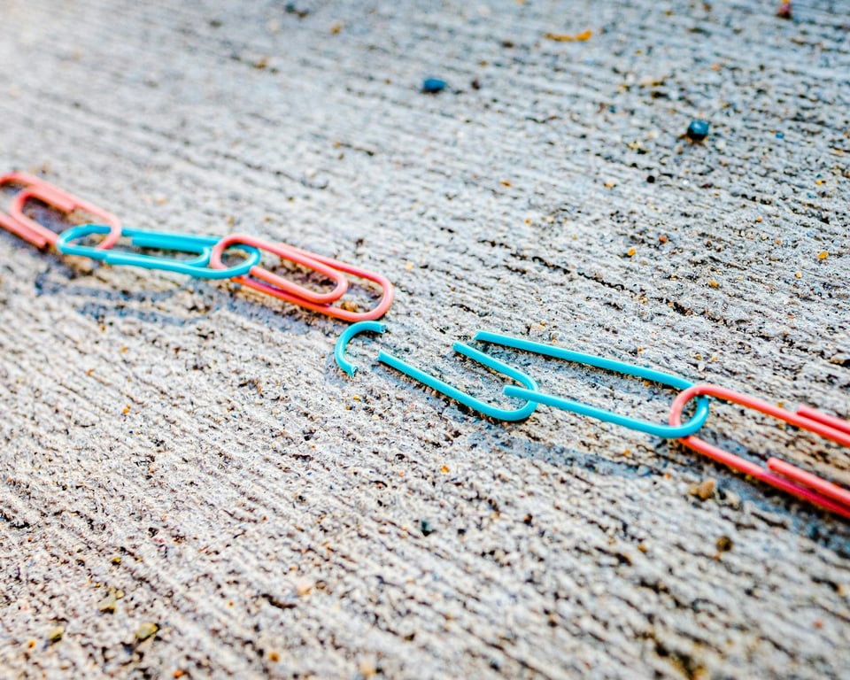 A chain made of colorful paperclips. Two paperclips in the center are broken. Photo by Jackson Simmer on Unsplash.