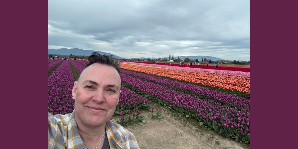 Leoh in front of rows of purple, orange, and red tulips