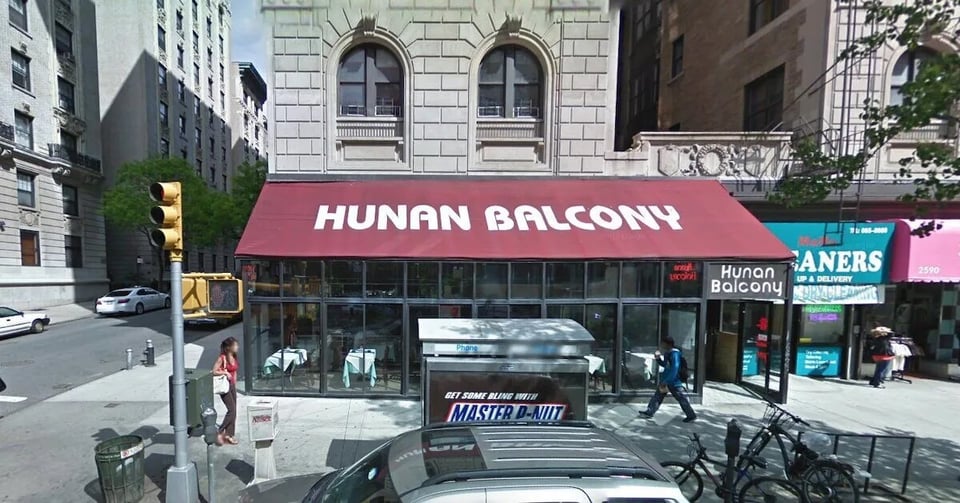 A Manhattan streetscape: a sidewalk, pedestrians walking by, and in the foreground, a restaurant with a red awning that reads "Hunan Balcony."