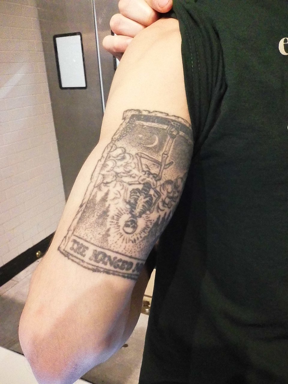 photo of a intricate tattoo of the tarot card of The Hanged Man, w/a skeleton in the figure of the man