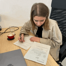 Animated gif of Julia sitting at a desk, signing the contract for her cooperative share