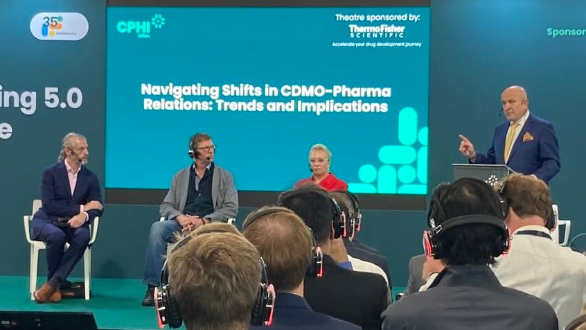 photo of 3 seated panelists and a standing moderator at a panel on Navigating Shifts in CDMO-Pharmaceuticals Relations: Trends and Implications