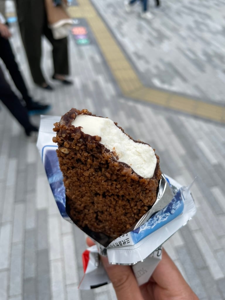 An enticing ice cream with bites taken out of it, revealing the creamy vanilla interior encased by the hard chocolate shell.