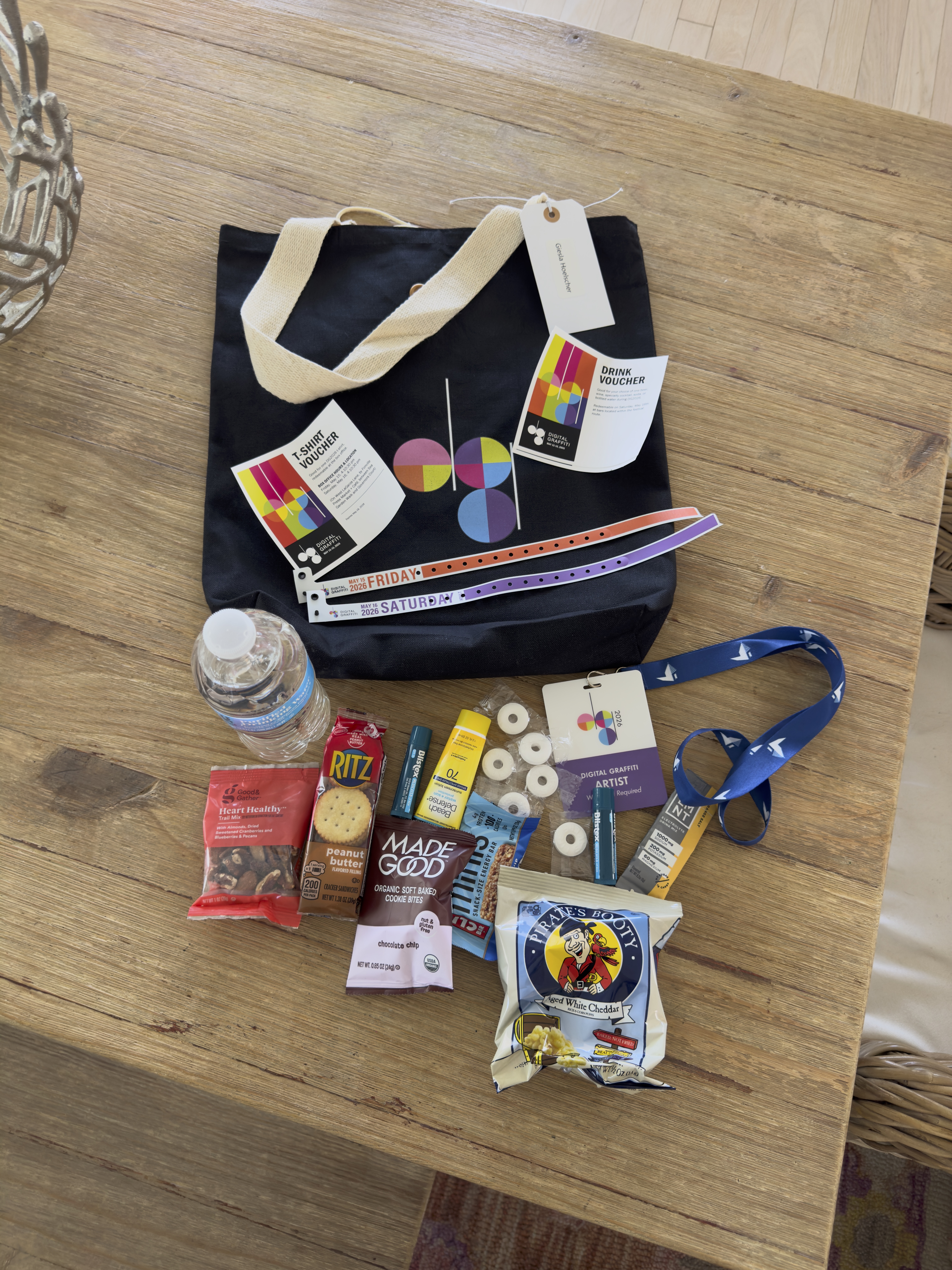 Black tote bag with snacks and other items on wood table