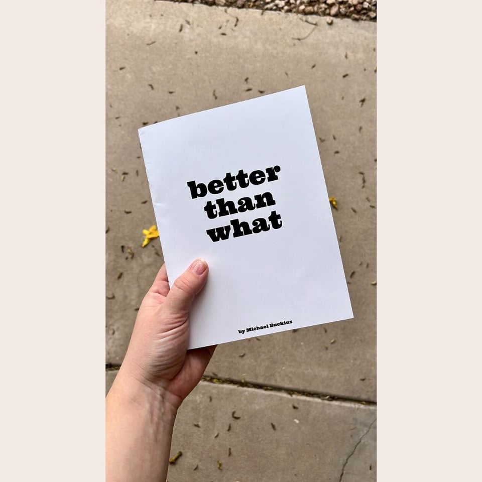 my hand holding a copy of Michael Buckius' new book of poetry Better Than What