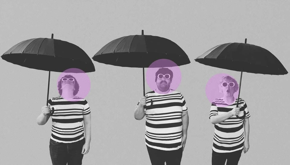 A black-and-white photo of three people standing in a line. Each wears a black-and-white striped shirt, black pants and is holding up a black umbrella. They have lavender circles on their faces like spotlights