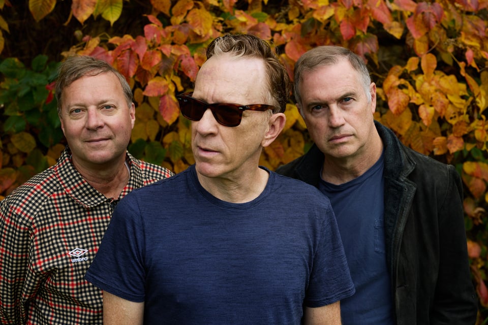 Three men comprising the band Buffalo Tom against a backdrop of autumn leaves.