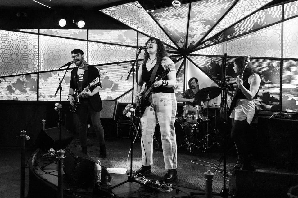 a black and white image of indie rock band Sorry Darling, with the led background of the Sultan Room behind them