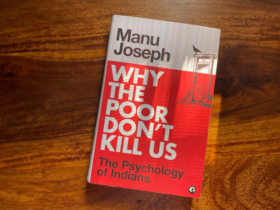 Shows the book 'Why the poor don't kill us' by Manu Joseph, lying on a wooden table
