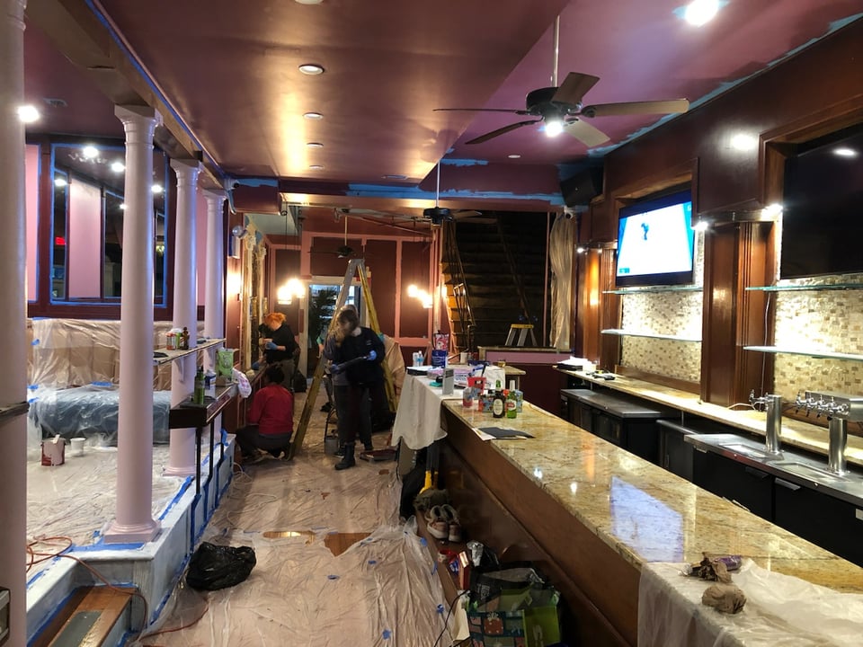 The bar mostly painted, seen from the front door, with deep burgundies, wines, and light pinks and mauves replacing the brighter blues and oranges. It looks more intimate and cozy. Plenty of unfinished paint on trims, and lots of plastic coverings still.