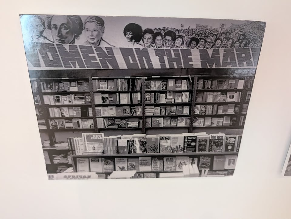A bookcase full of books, with WOMEN ON THE MARCH written on top, plus pictures of women marching and famous feminists in the forefront.