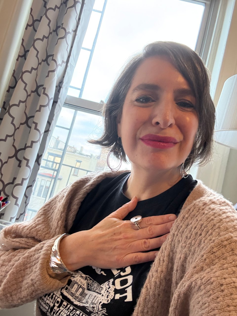 Amanda Schuster wearing a silver cuff bracelet and subway token ring by the window of her fire escape in Brooklyn