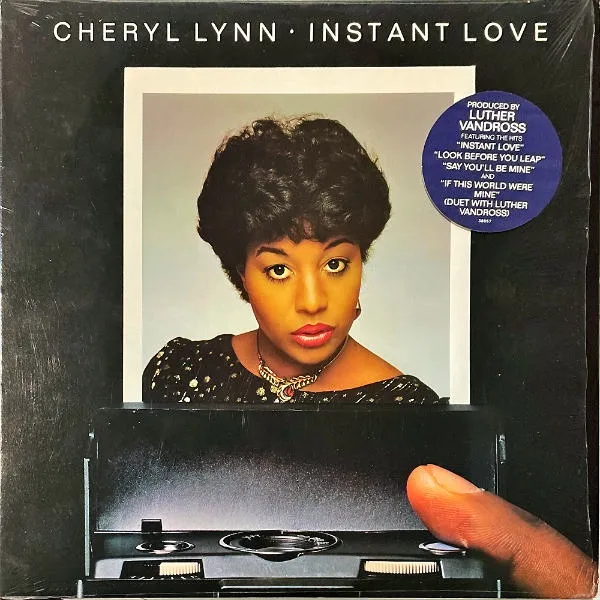 The cover of Instant Love, in which Cheryl Lynn's picture is emerging from some kind of mechanism with a finger poised over it. There's a sticker explaining that this LP is indeed produced by Luther Vandross, which would have made me buy this record instantly if I'd been buying albums in 1982.