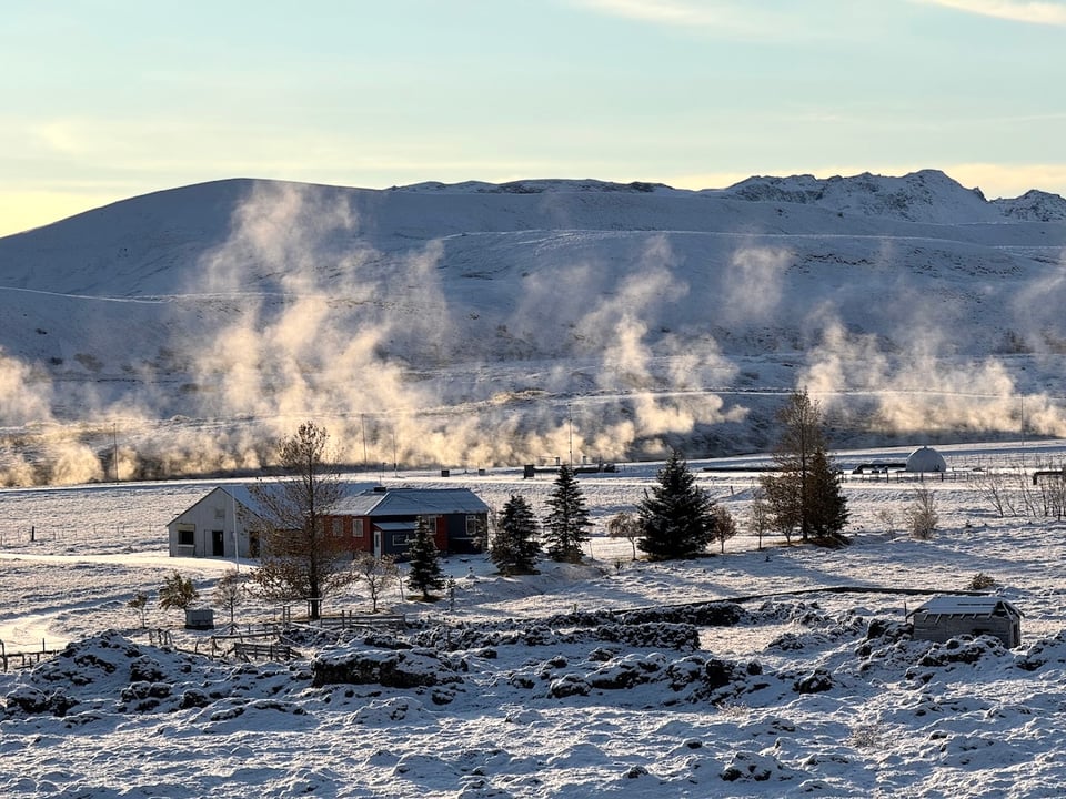 Steam rises over a snow landscape, near a geothermal plant in Iceland