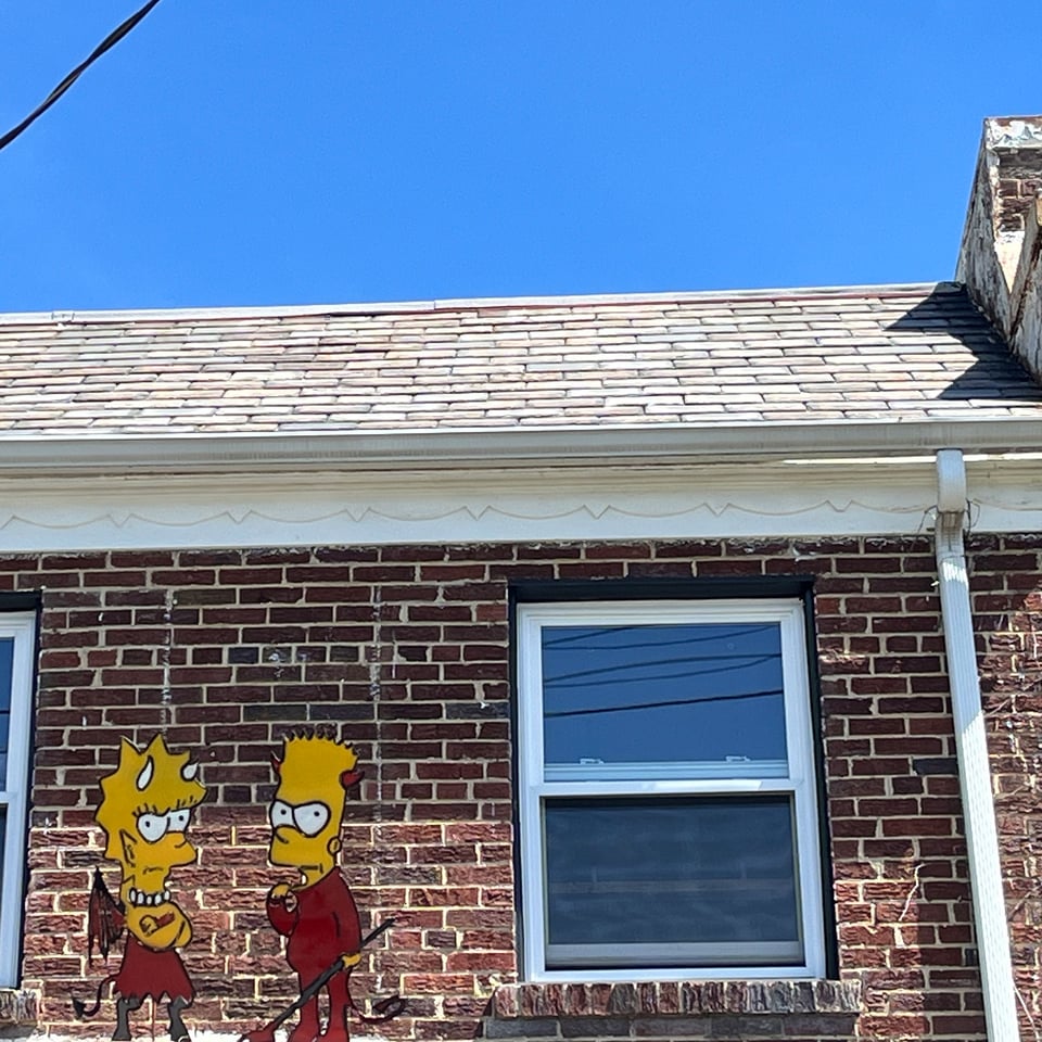 Devil versions of Lisa and Bart Simpson on a roof.