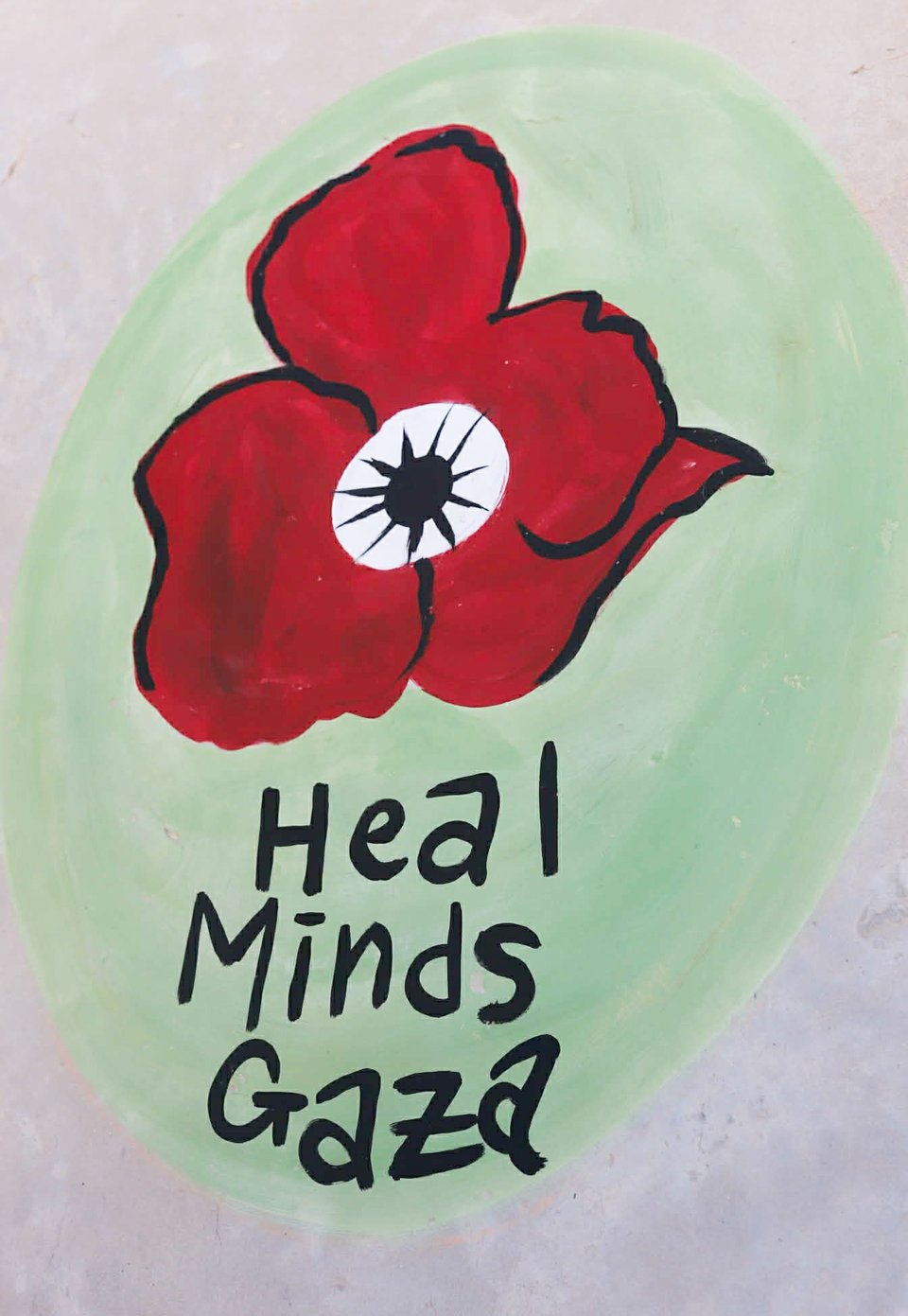Photo of the Heal Minds Gaza logo painted on a wall in Gaza: a green circle with a red anemone poppy at the center