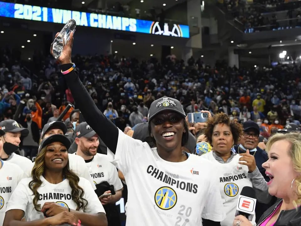 Kahleah Copper holds up the Finals MVP trophy in front of her team while celebrating the 2021 WNBA championship