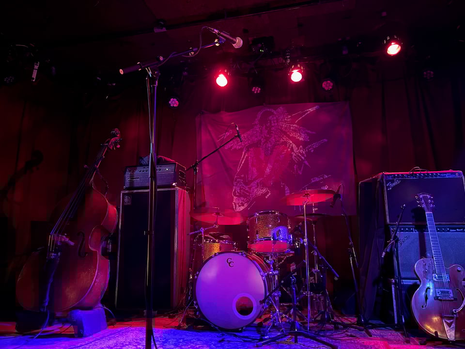 Image of musical instruments on a dark stage with red stage lights