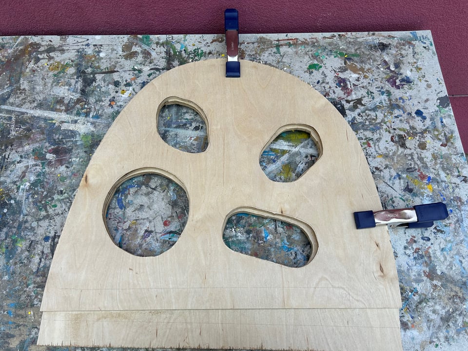 two pieces of wood clamped together, with holes cut out of the middle of both