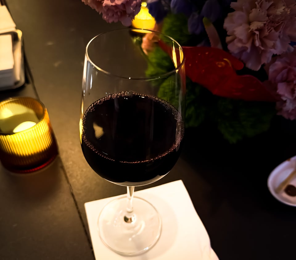 Glass of wine on candlelit bar with flowers