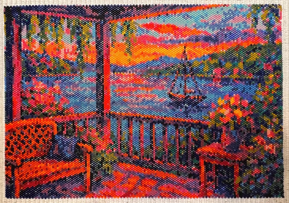 Abstract Sunset by Bay State Beadcraft. A scene of a porch with a bench, a table with a vase of flowers, and a sailboat in the background, all created with beads. Click image to view source.