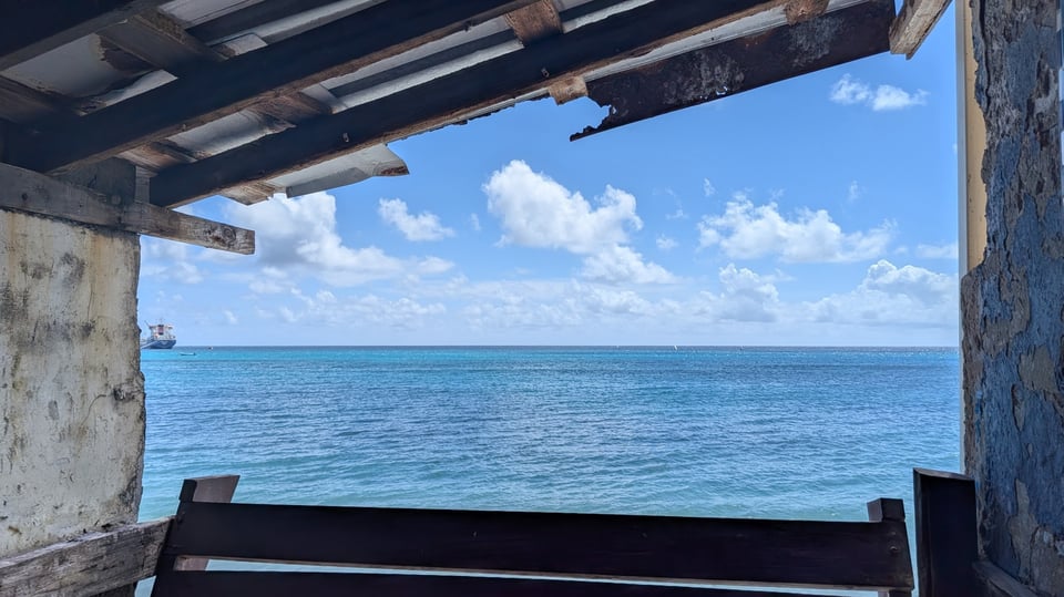 The blue ocean and blue sky with drifting cumulus clouds blowing east. I took this picture standing inside a restaurant, and the borders of the building are pictured here.