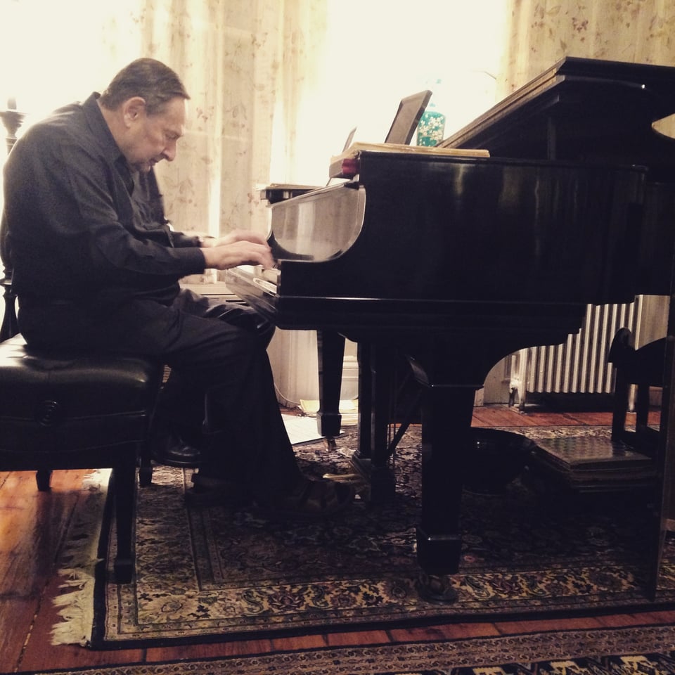 Man playing a Steinway piano in a parlor-like setting on oriental rug